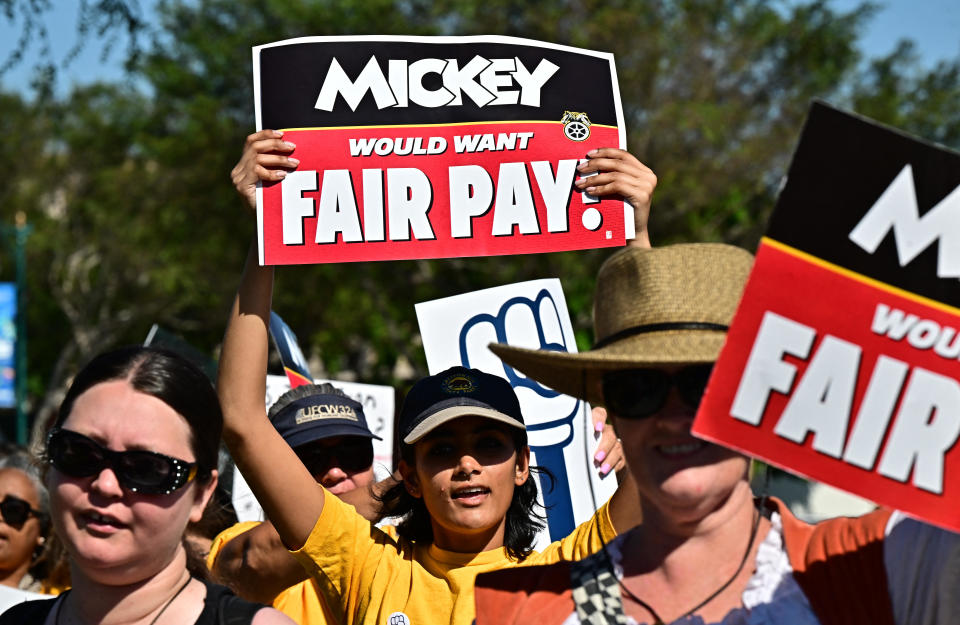 Disney employees hold signs as they gather outside the main gate of Disneyland Resort in Anaheim, California, on July 17, 2024, ahead of a planned strike authorization vote. / Credit: FREDERIC J. BROWN/AFP via Getty Images