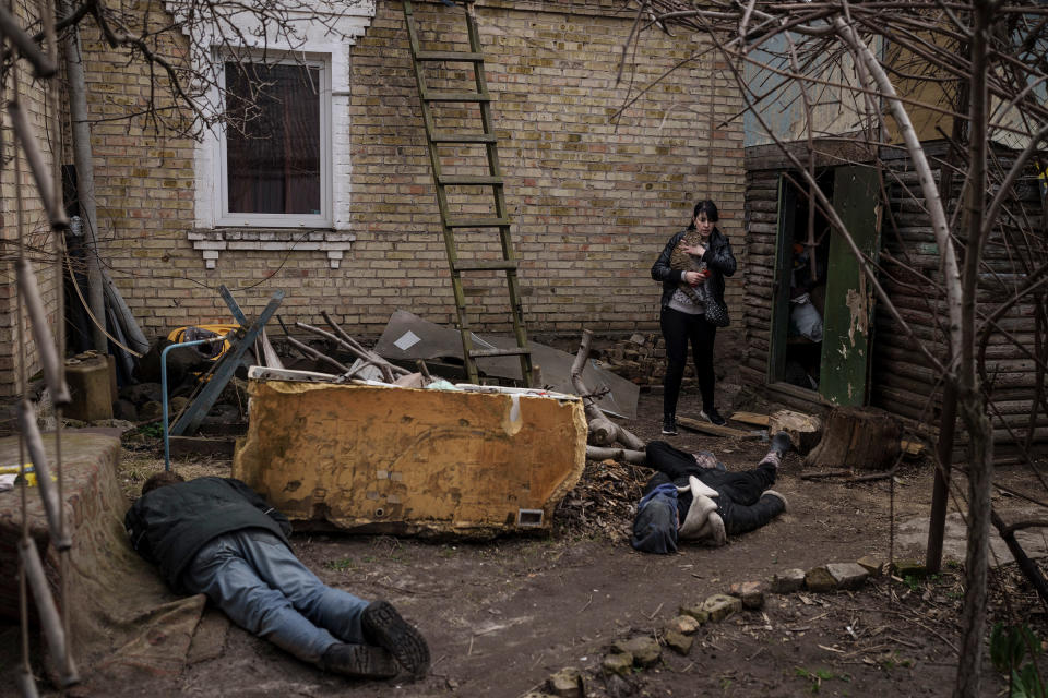 Ira Gavriluk holds her cat as she walks next to the bodies of her husband, brother, and another man, who were killed outside her home in Bucha, on the outskirts of Kyiv, Ukraine, April 4, 2022.<span class="copyright">Felipe Dana—AP</span>