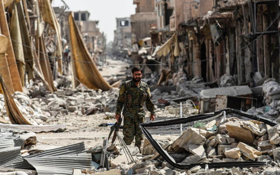 A member of the Syrian Democratic Forces (SDF) walks through the debris in the old city centre on the eastern frontline of Raqa  - AFP