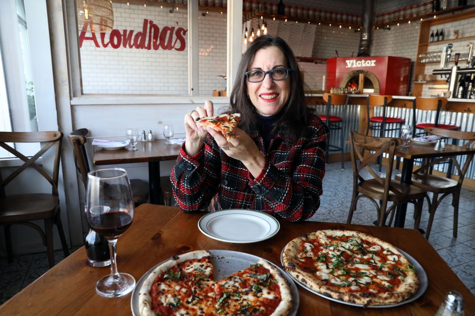 Lohud food reporter Jeanne Muchnick holds a gluten-free Margherita pizza slice at Alondra's restaurant in Larchmont Jan. 5, 2024. It was the best thing she ate this week.