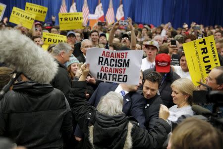 A protester holding a sign against racism and hatred is removed from U.S. Republican presidential candidate Donald Trump's campaign rally at the University of Iowa in Iowa City, Iowa, January 26, 2016. REUTERS/Scott Morgan