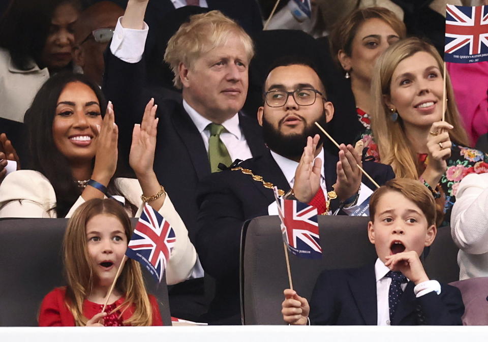 Prince George, right, and Princess Charlotte watch the Platinum Jubilee concert taking place in front of Buckingham Palace, London, Saturday June 4, 2022, on the third of four days of celebrations to mark the Platinum Jubilee. The events over a long holiday weekend in the U.K. are meant to celebrate Queen Elizabeth II's 70 years of service. (Henry Nicholls/Pool via AP)