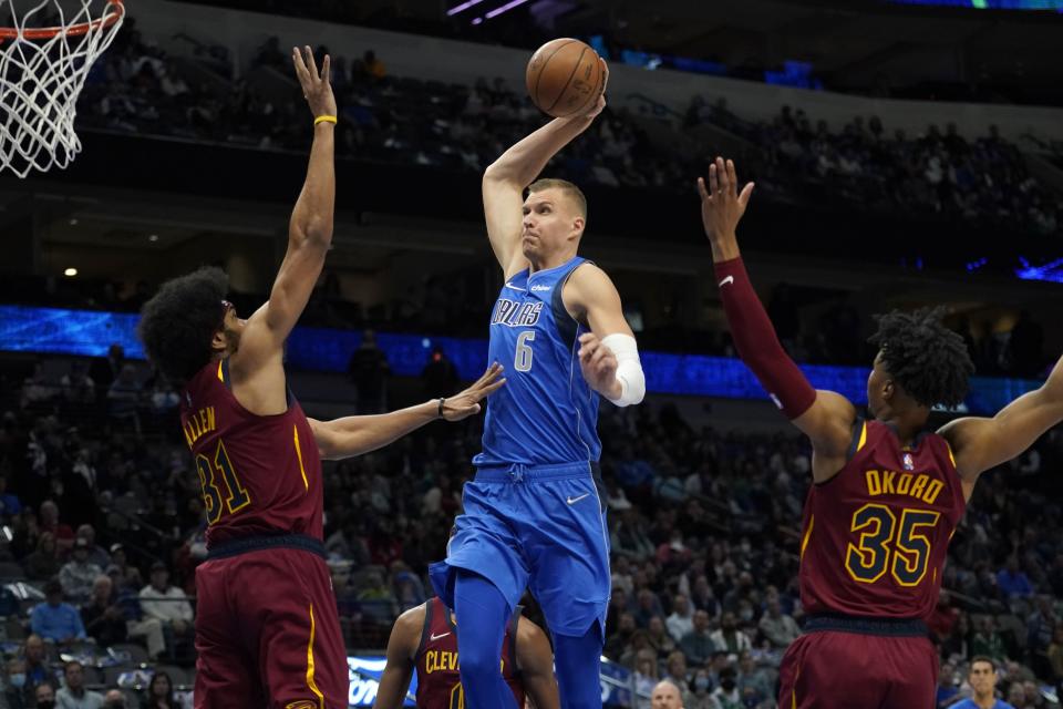 Dallas Mavericks forward Kristaps Porzingis (6) goes up to dunk between Cleveland Cavaliers' Jarrett Allen (31) and Isaac Okoro (35) in the first half of an NBA basketball game in Dallas, Monday, Nov. 29, 2021. (AP Photo/Tony Gutierrez)