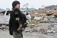 A man carries his dog in the city of Ofunato. Japanese crews grappling with the world's worst nuclear incident since Chernobyl temporarily pulled out Wednesday as radiation rose following feared damage to a reactor containment vessel
