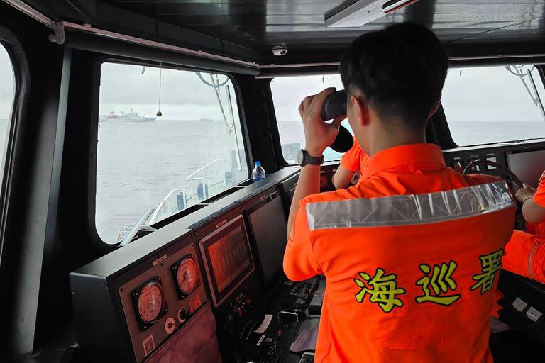 Esta fotografía tomada y publicada por la Guardia Costera de Taiwán el 23 de mayo de 2024 muestra a un miembro de las fuerzas armadas taiwanesas monitoreando un barco militar chino mientras navega unas pocas millas al norte de la isla Pengjia, frente a la costa del norte de Taiwán.