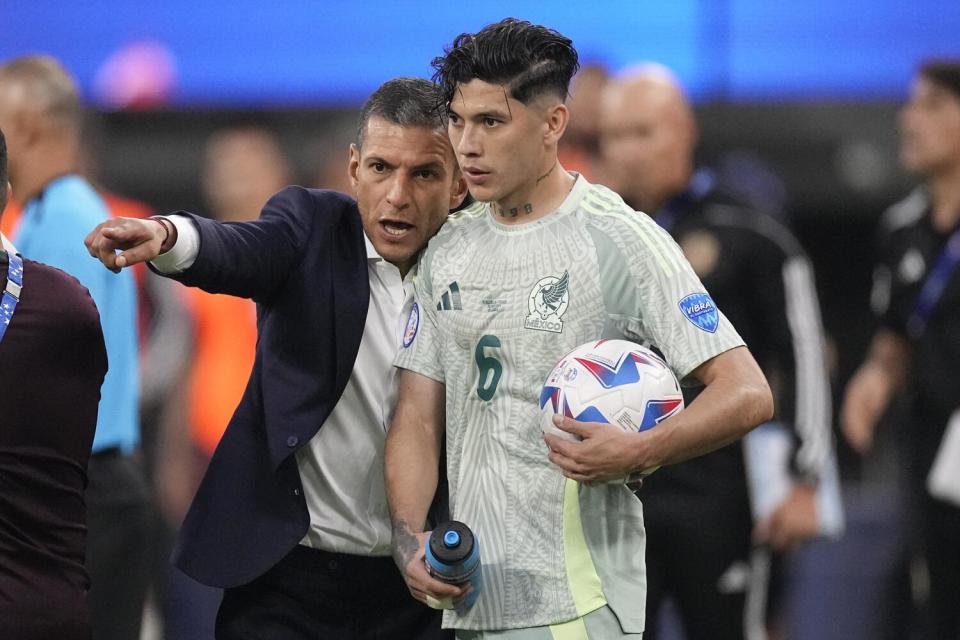 Mexico coach Jaime Lozano talks to Gerardo Arteaga during Wednesday's Copa América match against Venezuela at SoFi Stadium.