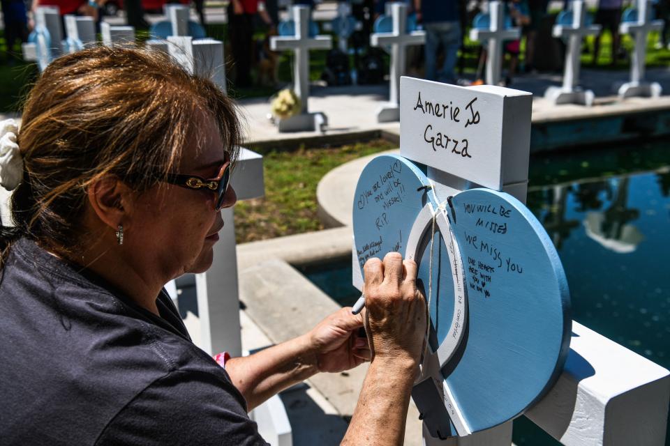 A woman writes on a heart at a makeshift memorial outside Uvalde County Courthouse in Uvalde, Texas, on May 26.