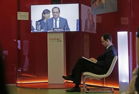 An observer sits at the Moroccan pavillon and listens to French President Francois Hollande speech broadcast from the conference room at the World Climate Change Conference 2015 (COP21) in Le Bourget, near Paris, France, December 12, 2015. Morocco will host the COP in 2016. REUTERS/Jacky Naegelen