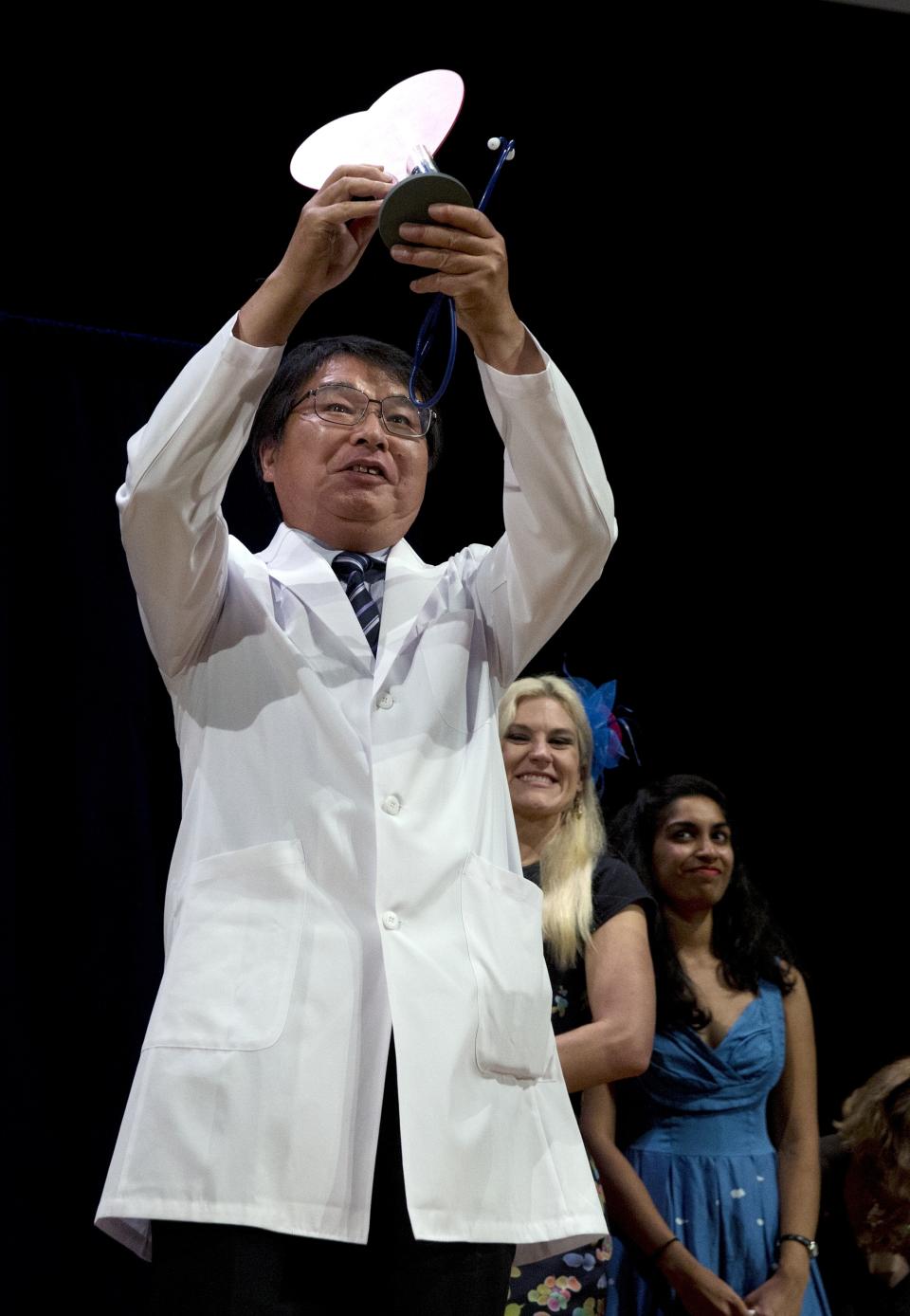 Akira Horiuchi, of Japan, holds up his Ig Nobel for medical education during award ceremonies at Harvard University in Cambridge, Mass., Thursday, Sept. 13, 2018. Horiuchi won for devising a revolutionary new way to give yourself a colonoscopy. (AP Photo/Michael Dwyer)