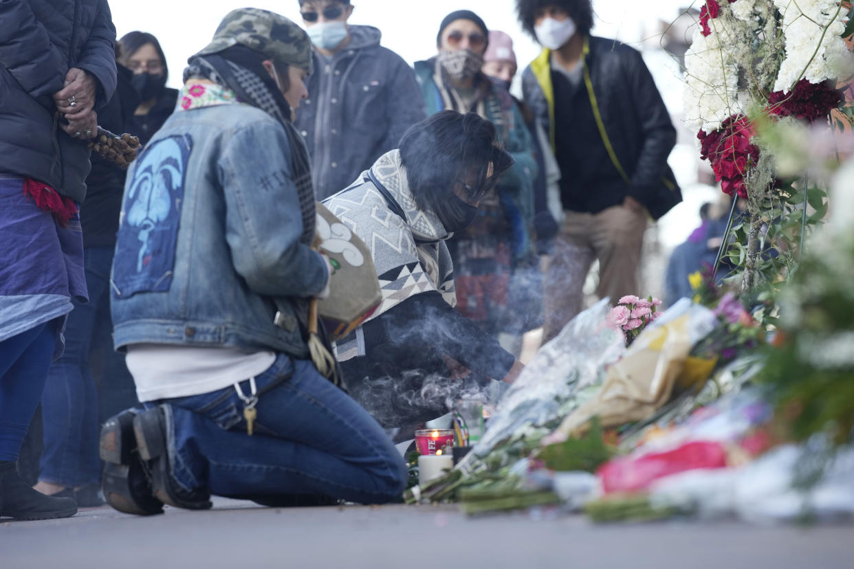 Mourners burn incense as they gather outside the door of a tattoo parlor along South Broadway Tuesday, Dec. 28, 2021, in Denver, one of the scenes of a shooting spree that left multiple people dead—including the suspected shooter Monday evening—and a few other people wounded. The spree spread from the core of Denver to the western suburb of Lakewood where the suspect was shot and killed by police near a busy intersection in a bustling shopping district. (AP Photo/David Zalubowski)