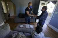 Abdul, right, who worked as a mechanic before he left Kabul, Afghanistan with his family about a month ago, shakes hands with Jesse Robbins, left, Thursday, Sept. 16, 2021, after Robbins helped activate internet service in the rental house he owns along with his wife, Thuy Do, who was nine years old when her family arrived in the United States from Vietnam in the 1980s. Do and Robbins have offered their vacant rental home to refugee resettlement groups to house newly arriving Afghans in need of a place to stay. (AP Photo/Ted S. Warren)