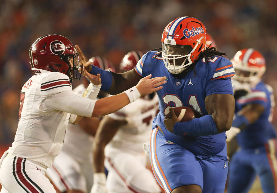 Florida defensive lineman Desmond Watson (21) stiff arms South Carolina quarterback Spencer Rattler (7) after recovering a fumble during the second half of an NCAA college football game, Saturday, Nov. 12, 2022, in Gainesville, Fla. (AP Photo/Matt Stamey)