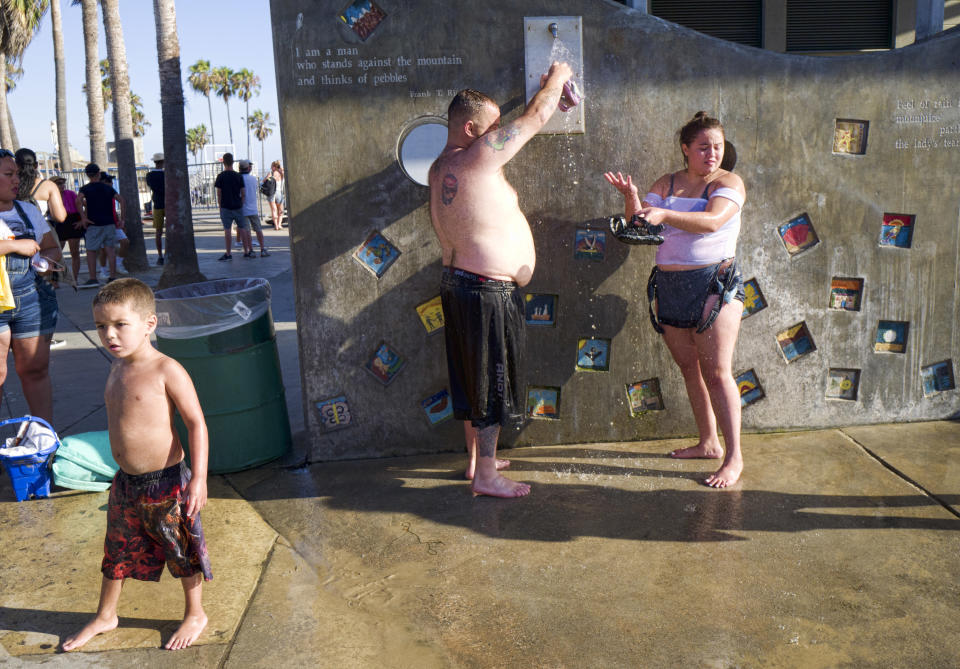 A family rinses and cools off under an outdoor shower at Venice Beach in Los Angeles, Tuesday, July 24, 2108. Scorching heat radiated across the U.S. Southwest on Tuesday, with the highest temperatures expected in California's Death Valley during a week that forecasters say could prove to be the region's hottest this year. (AP Photo/Richard Vogel)