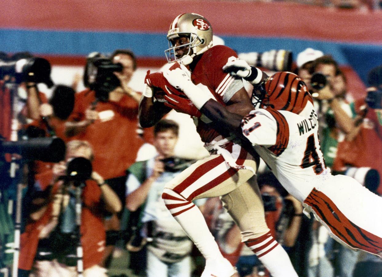 San Francisco 49ers wide receiver Jerry Rice (80) runs with the football after making a catch and drags Bengals defensive back Solomon Wilcots (41) along the way during the 4th quarter of the 49ers 20-16 victory over the Cincinnati Bengals in 1989