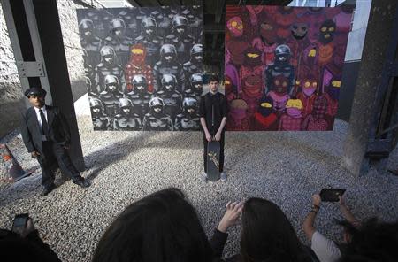 A man poses for a photo in front of an art installation by British graffiti artist Banksy in New York October 18, 2013. REUTERS/Carlo Allegri