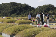 Family members wearing face masks pay respects at their ancestral cemetery ahead of Chuseok holiday, the Korean version of Thanksgiving Day, at a cemetery in Paju, South Korea, Sunday, Sept. 27, 2020. South Korea's national cemeteries will be closed during the upcoming Chuseok holiday during the five-day holidays from Sept. 30 to Oct. 4 to prevent the spread of the coronavirus. (AP Photo/Ahn Young-joon)