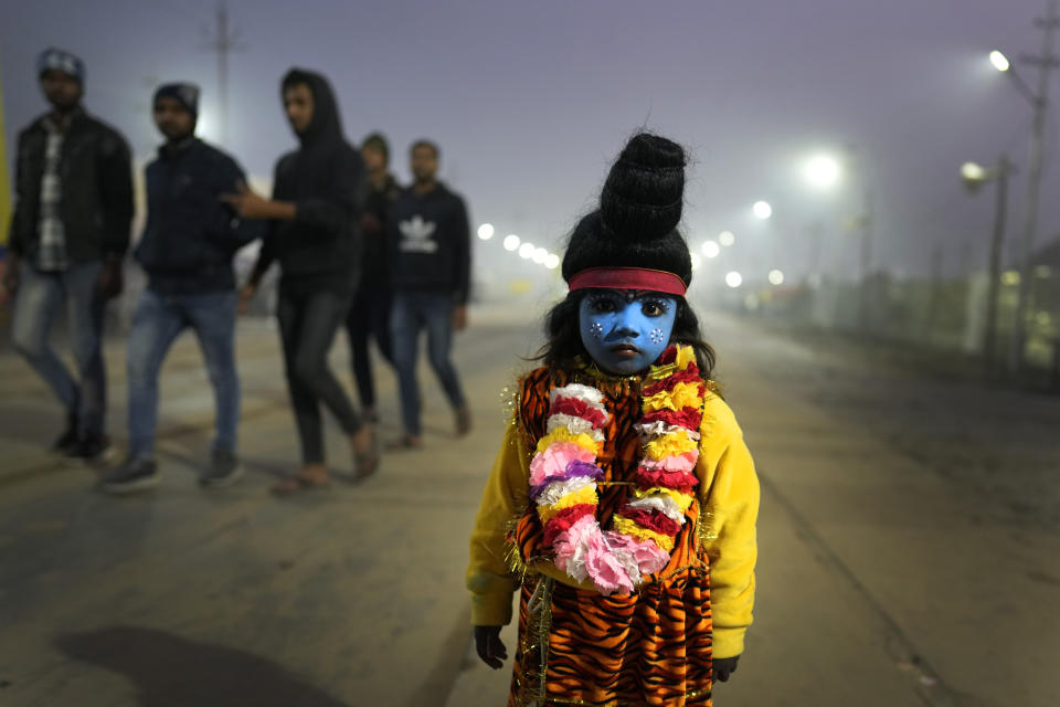 A child dressed as Hindu God Shiva begs for alms from devotees at the Sangam, the confluence of three rivers — the Ganges, the Yamuna and the mythical Saraswati, on the Makar Sankranti festival during the annual traditional fair of Magh Mela in Prayagraj, in the northern Indian state of Uttar Pradesh, Sunday, Jan. 14, 2024. Hundreds of thousands of Hindu pilgrims are expected to take dips in the confluence, hoping to wash away sins during the month-long festival. (AP Photo/Rajesh Kumar Singh)