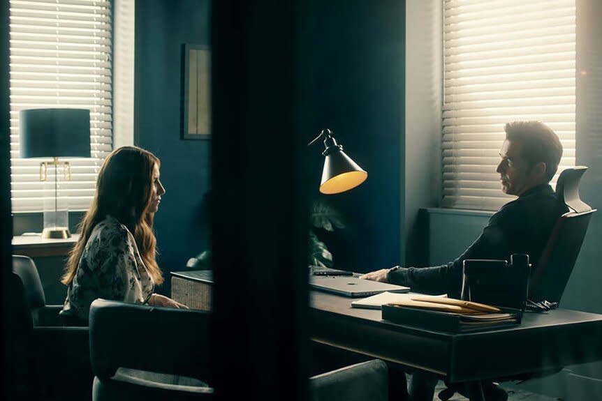 (l-r) Susan Ireland (Sarah Levy) and Luke Roman (Tim Rozon) speak over a desk in SurrealEstate 201 