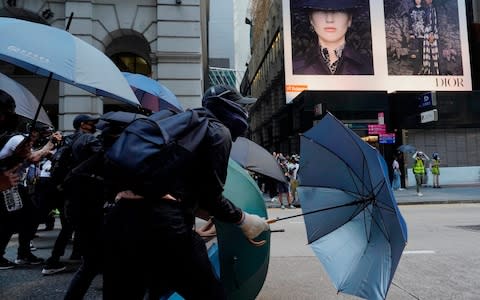 Protesters with umbrellas attempt to face off riot police in Hong Kong on Monday - Credit: &nbsp;Vincent Yu/AP