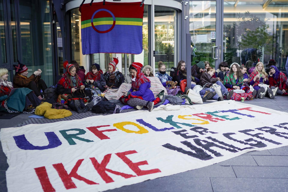 FILE - Activists wearing traditional Sami outfits sit in protest outside the entrance of Statkraft, a state-owned company that operates 80 of the wind turbines at Fosen, in central Norway's Fosen district on Oct. 12, 2023. Norway reached Wednesday an agreement with the Sami people ending a dispute over Indigenous right that led to activists blocking several entrances to Norwegian government offices over a wind farm that they say hinders the rights of the Indigenous people to raise reindeer. At the center of the dispute are the 151 turbines of Europe’s largest onshore wind farm, which is located in central Norway’s Fosen district, about 450 kilometers (280 miles) north of the capital, Oslo." (Cornelius Poppe/NTB Scanpix via AP, File)