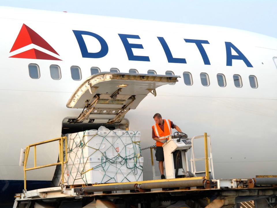 Worker loading Delta cargo onto an aircraft.