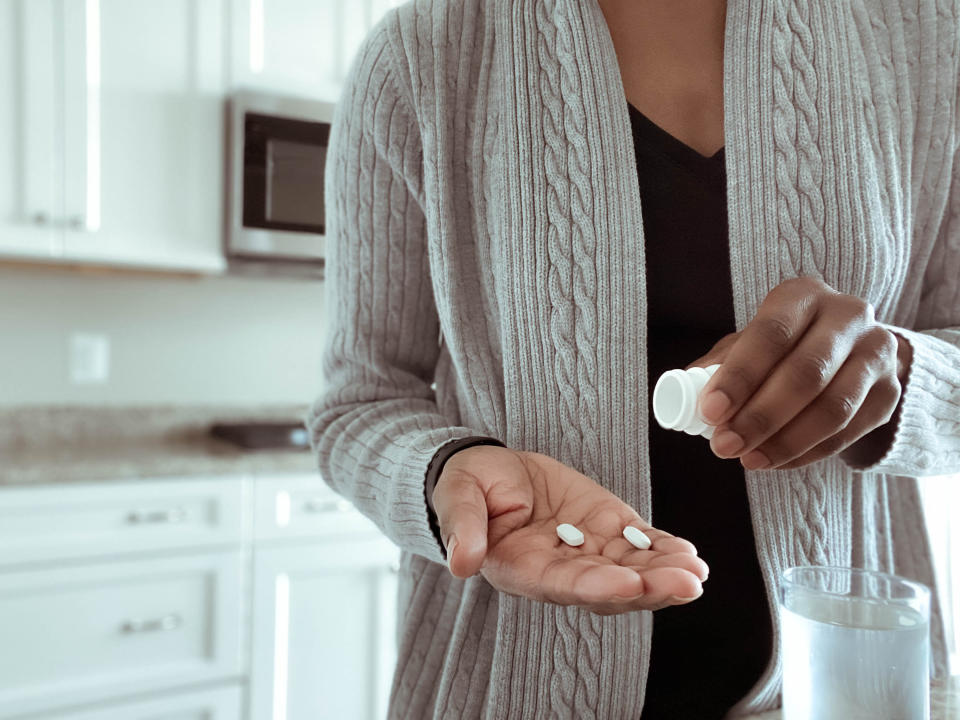Close-up of unrecognizable woman pouring pills into palm of hand antidepressants