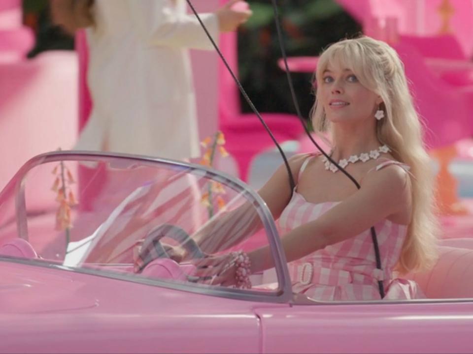 Margot Robbie driving in a pink car in Barbie