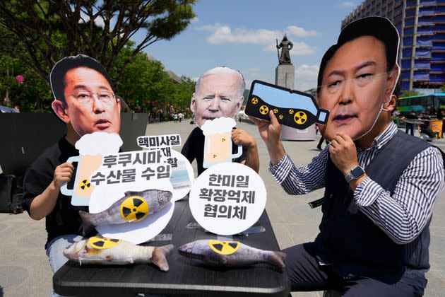 Protesters — wearing masks of political leaders from Japan, the U.S., and South Korea — are pictured during a rally denouncing a summit between the countries, in Seoul, South Korea, on May 19. They oppose the nations' military alliance and the release of treated radioactive water from a Fukushima nuclear power plant. The text reads, 