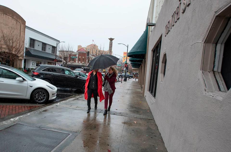 Two women share an umbrella on 10th Street in Modesto, Calif., on Monday, Dec. 13, 2021.