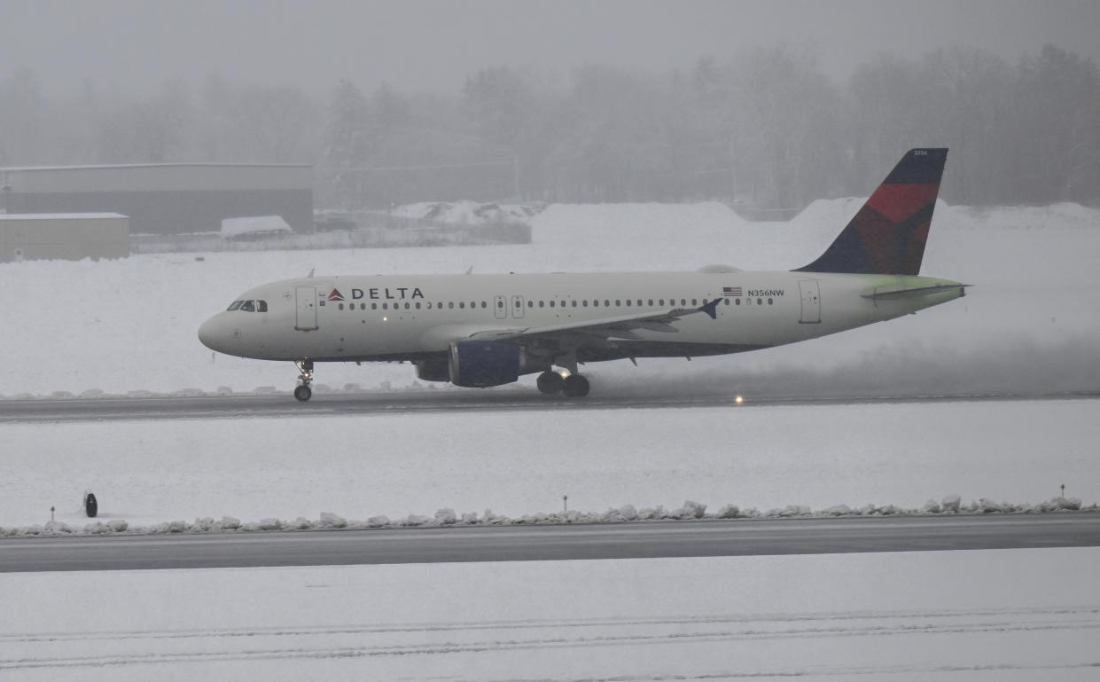 A Delta airline flight lands as Crews remove snow from the Albany International Airport during a winter snow storm Tuesday, March 14, 2023, in Albany, N.Y. (AP Photo/Hans Pennink)