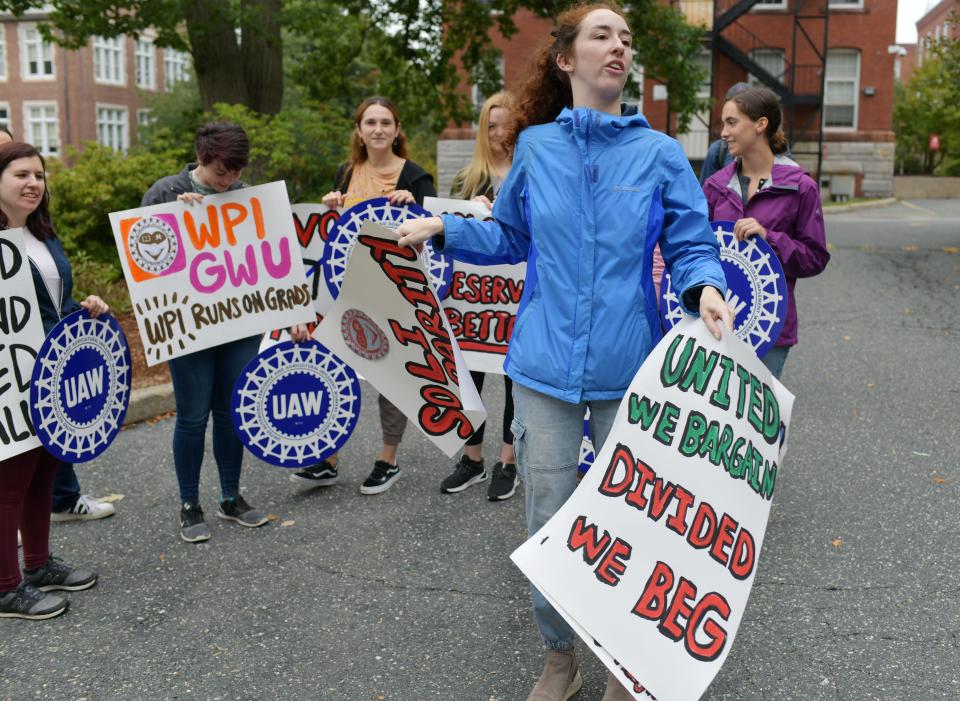 A WPI graduate worker distributes signs for a rally to unionize Monday.