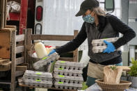 In this Thursday, May 28, 2020 photo, Beth Shiller of Dandelion Spring Farm stacks eggs at her farmer's market stand in Rockland, Maine. From meat to seafood and produce, farmers and fishermen have lost their restaurant business amid the coronavirus shutdowns and had to pivot quickly to sell more to stores or directly to consumers. (AP Photo/Robert F. Bukaty)