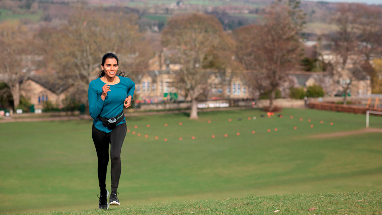  Woman running up a hill in a park. 