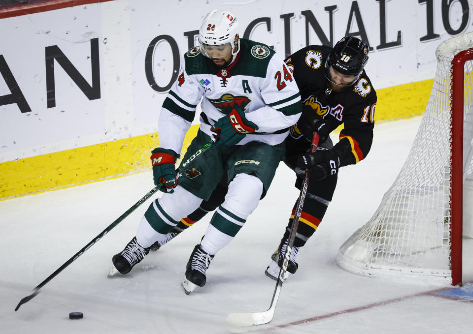 Minnesota Wild defenceman Matt Dumba, left, is checked by Calgary Flames forward Jonathan Huberdeau during the third period of an NHL hockey game Saturday, March 4, 2023, in Calgary, Alberta. (Jeff McIntosh/The Canadian Press via AP)