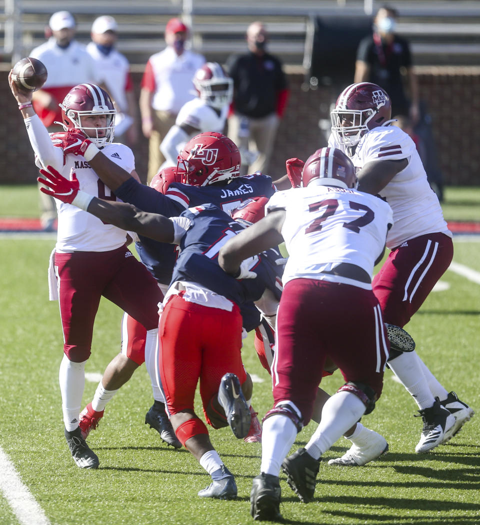 Massachusetts quarterback Garrett Dzuro (9) makes a pass under pressure during the first half of a NCAA college football game against Liberty on Friday, Nov. 27, 2020, at Williams Stadium in Lynchburg, Va. (AP Photo/Shaban Athuman)