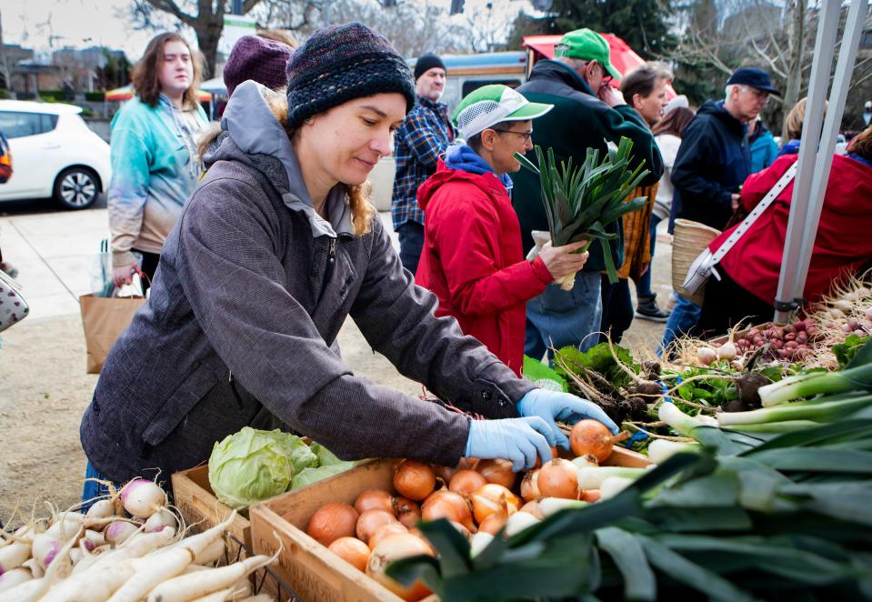 Ema Koziatek reorganizes produce at the Groundwork Organics farm stand on the opening day of the Lane County Farmers Market in Eugene on Feb. 4.