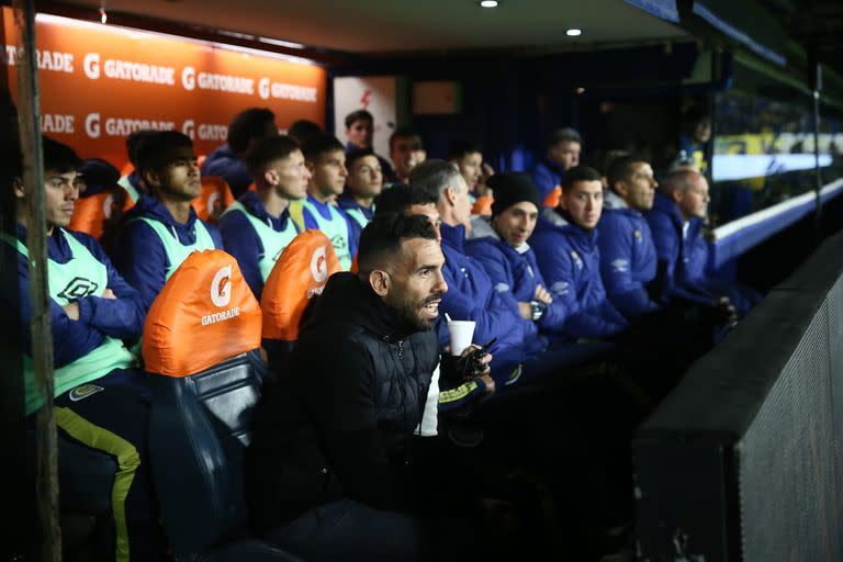 Una imagen atípica: Carlos Tevez en el banco de suplentes visitantes de la Bombonera