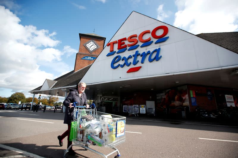 FILE PHOTO: A woman pushes a shopping cart as she walks past a Tesco supermarket in Hatfield