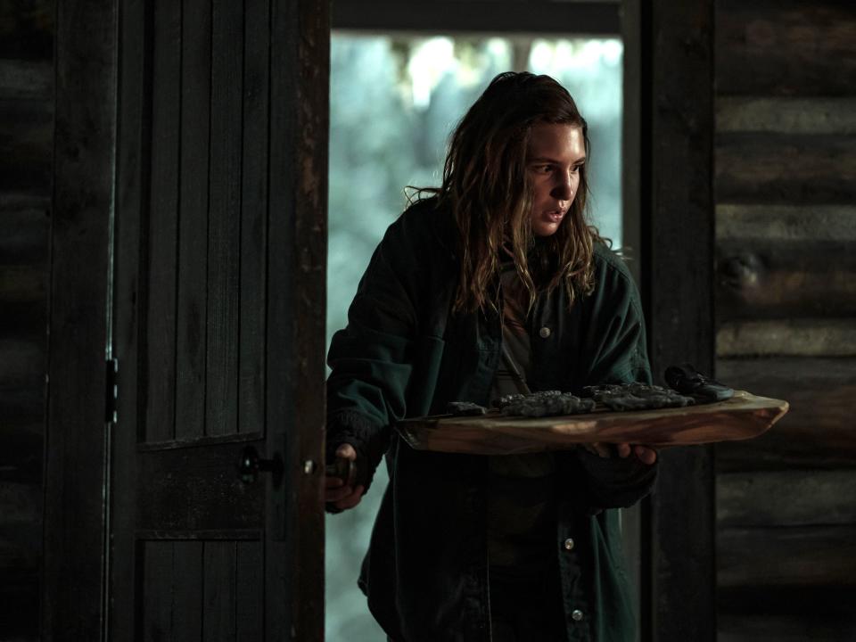 Shauna (Sophie Nélisse) walks into the cabin holding a tray of meat looking shocked in this still from season two, episode one of "Yellowjackets."