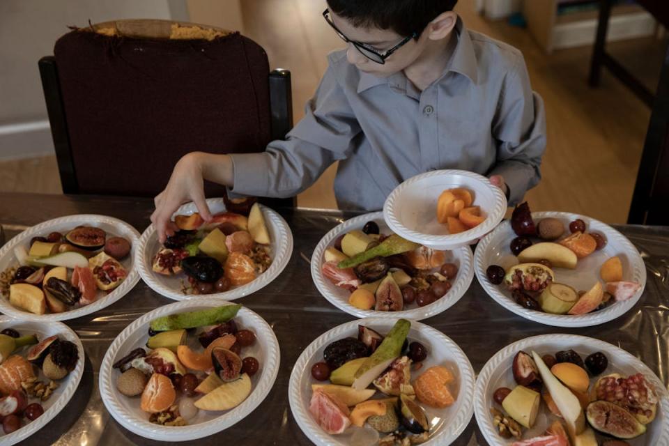 A boy prepares food for his family’s Tu BiShvat celebration in London. <a href="https://www.gettyimages.com/detail/news-photo/mendel-wallenberg-arranges-15-different-fruits-on-plates-as-news-photo/1299120906?phrase=tu%20bishvat%20israel&adppopup=true" rel="nofollow noopener" target="_blank" data-ylk="slk:Dan Kitwood/Getty Images;elm:context_link;itc:0;sec:content-canvas" class="link ">Dan Kitwood/Getty Images</a>