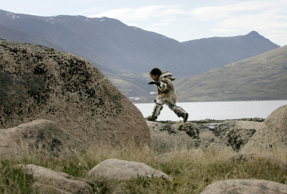 An Inuit girl dressed in traditional clothing plays on rocks in Pangnirtung, Nunavut July 5, 2007. REUTERS/Chris Wattie (CANADA)