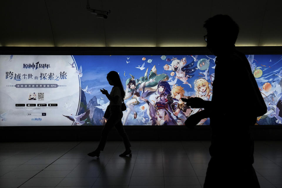 Commuters walk by a computer and mobile phone's RPG games advertised at a subway station in Beijing Tuesday, Sept. 14, 2021. Chinese regulators have set up a platform that allows the public to report on gaming companies they believe are violating restrictions on online game times for children. (AP Photo/Andy Wong)