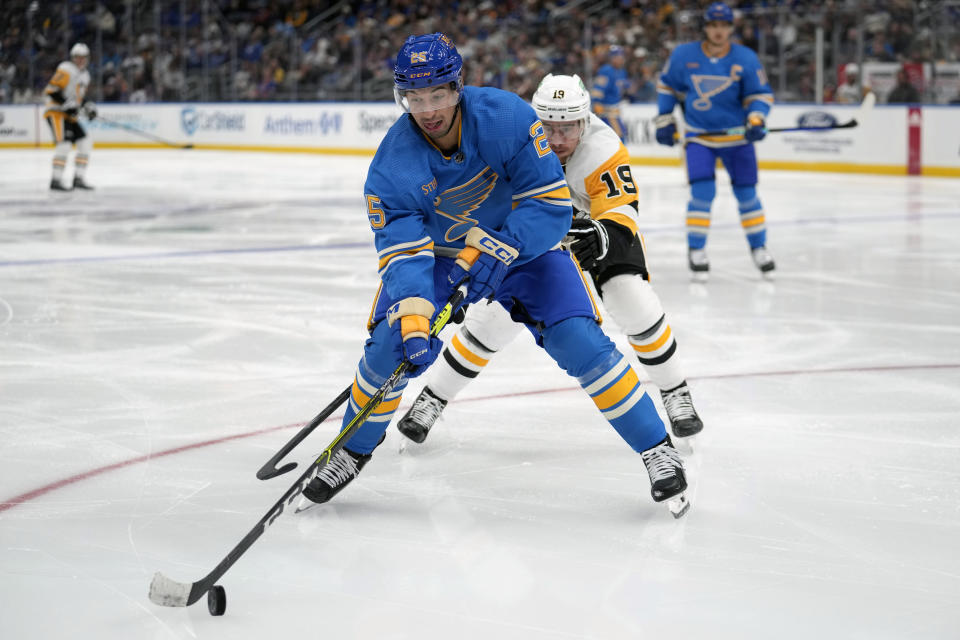 St. Louis Blues' Jordan Kyrou (25) handles the puck as Pittsburgh Penguins' Reilly Smith (19) defends during the third period of an NHL hockey game Saturday, Oct. 21, 2023, in St. Louis. (AP Photo/Jeff Roberson)