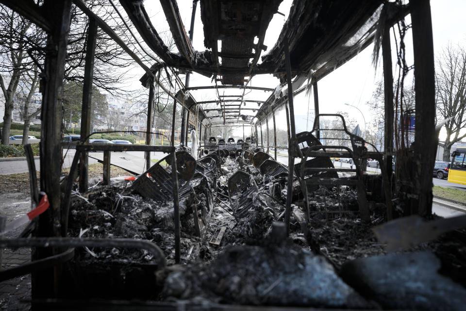 A burned-out bus stands partly beneath a residential building in the district Neukoelln in Berlin, Germany, Tuesday, Jan. 3, 2023. People across Germany on Saturday resumed their tradition of setting off large numbers of fireworks in public places to see in the new year. The bus was set on fire during the New Year's celebrations. (AP Photo/Markus Schreiber)