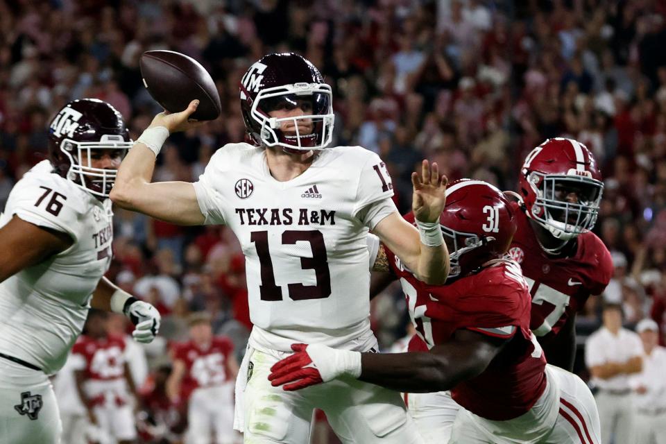Haynes King throws a pass while pressured by Alabama's Will Anderson during an October 2022 game. King has since transferred from Texas A&M to Georgia Tech.