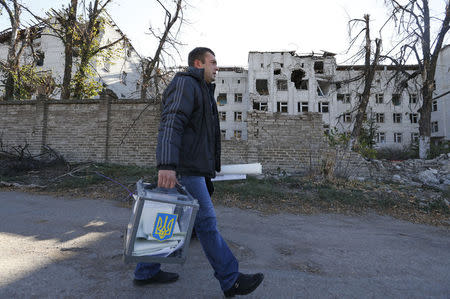 A member of an election commission carries documents and a mobile ballot box as he walks to visit local residents during a parliamentary election in the village of Semyonovka near Slaviansk, eastern Ukraine, October 26, 2014. REUTERS/Vasily Fedosenko