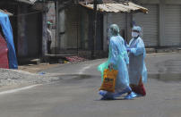 Indian health workers walk inside a containment zone during lockdown to prevent the spread of new coronavirus in Hyderabad, India, Sunday, April 26, 2020. A month long restrictions in this country of 1.3 billion people have been eased somewhat by allowing neighborhood shops to reopen and manufacturing and farming activities to resume in rural areas to help millions of poor daily wage earners. (AP Photo/Mahesh Kumar A.)