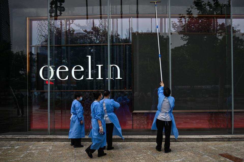 Workers wearing protective gear clean the windows outside a closed shopping mall during a Covid-19 coronavirus lockdown in the Jing'an district of Shanghai on May 30, 2022.