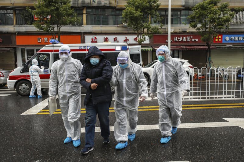 Medical professionals in protective gear help a patient in Wuhan. Source: AP