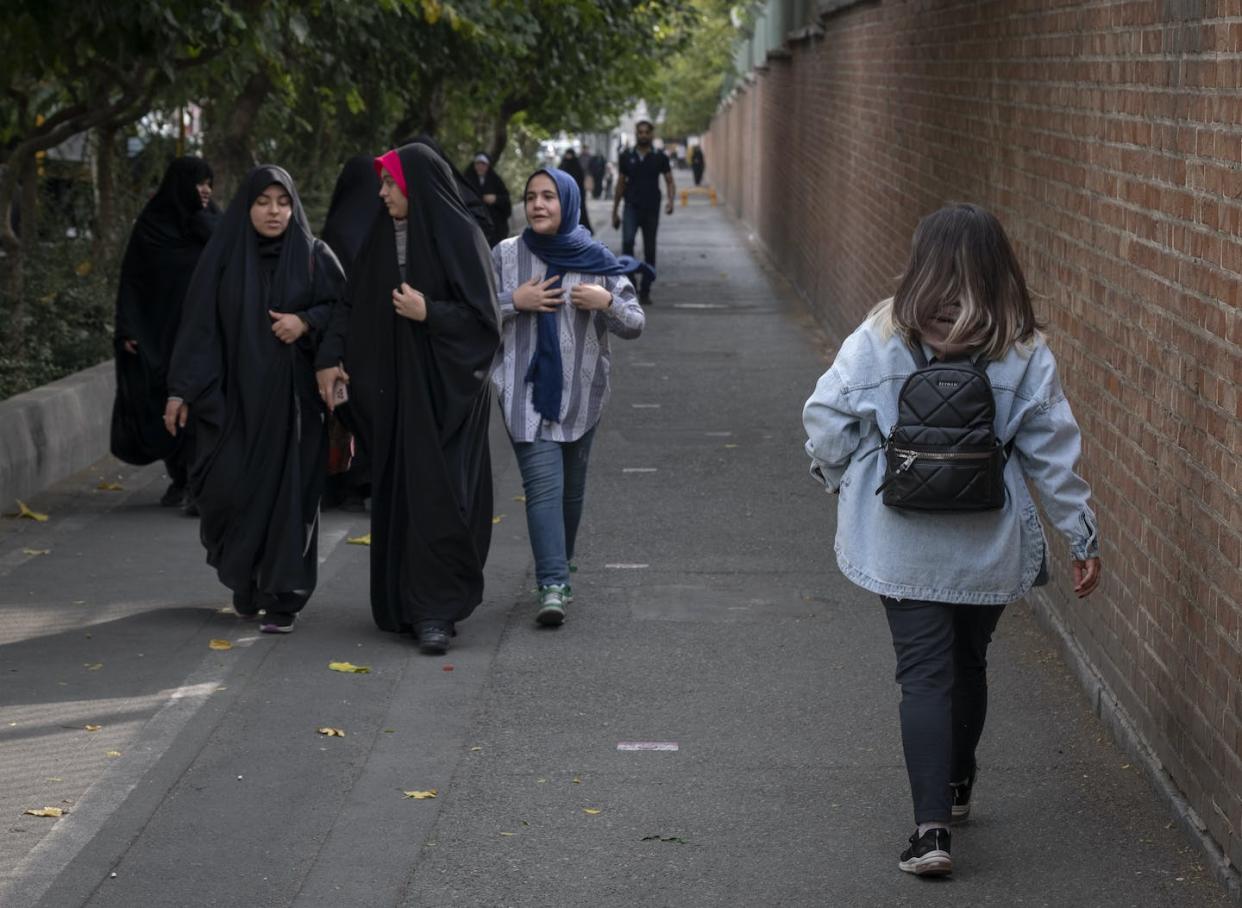 An Iranian woman not wearing a mandatory headscarf walks past a group of young women who cover their hair in November 2023. <a href="https://www.gettyimages.com/detail/news-photo/young-iranian-woman-without-wearing-a-mandatory-headscarf-news-photo/1761137953?adppopup=true" rel="nofollow noopener" target="_blank" data-ylk="slk:Morteza Nikoubazl/NurPhoto via Getty Images;elm:context_link;itc:0;sec:content-canvas" class="link ">Morteza Nikoubazl/NurPhoto via Getty Images </a>